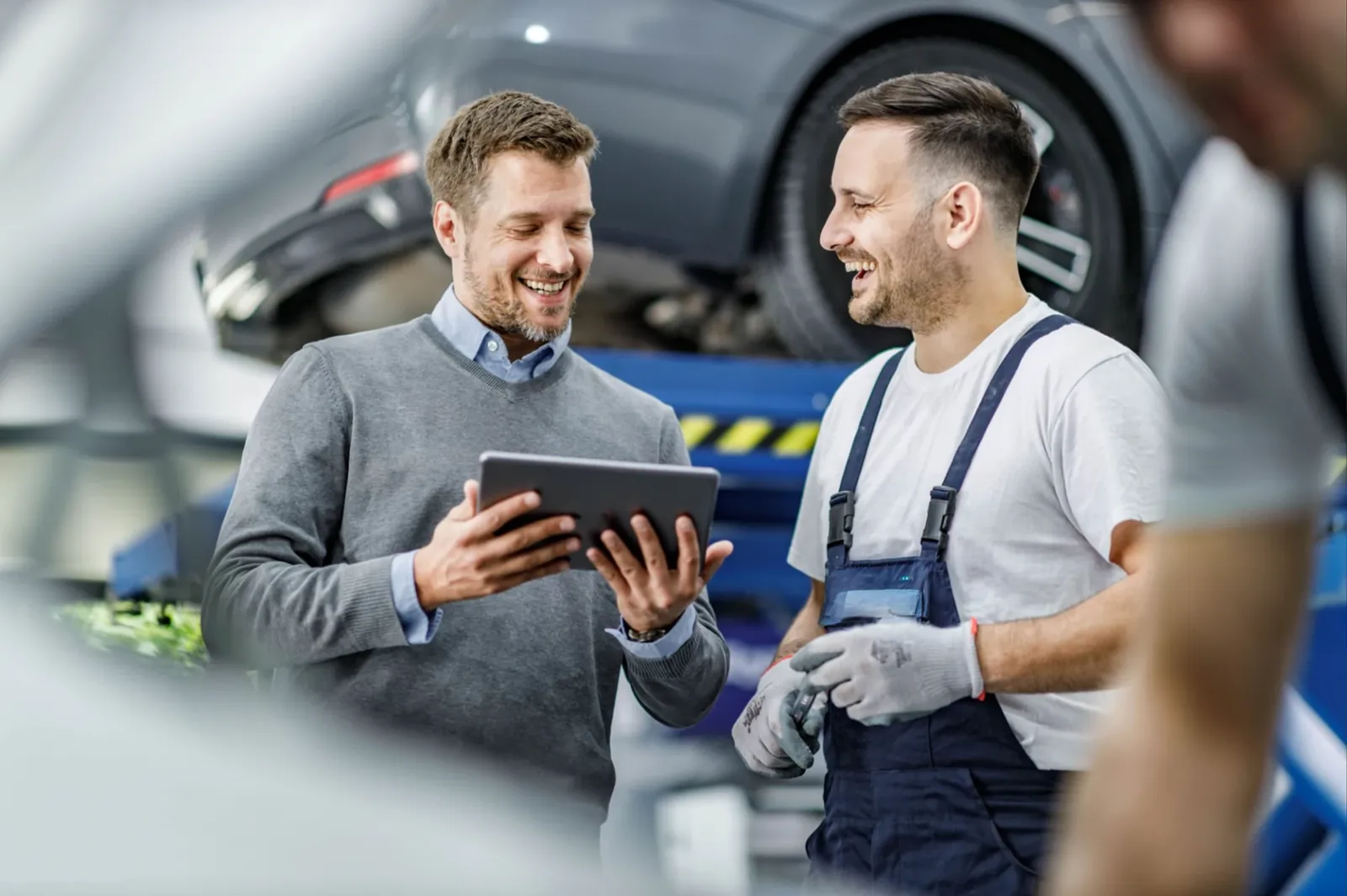 Kfz-Meister bespricht mit einem Kunden die Reparatur am Tablet